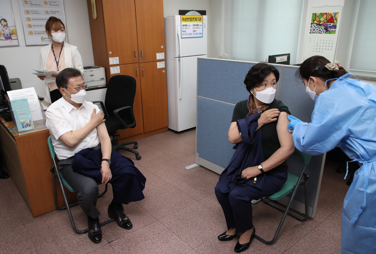 President Moon Jae-in (left) watches his wife Kim Jung-sook being administered a shot of AstraZeneca‘s COVID-19 vaccine after receiving his own at a public health facility in Seoul on Tuesday. (Yonhap)