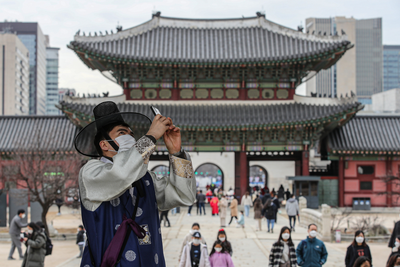 삼일절 연휴인 28일 오후 서울 종로구 경복궁을 찾은 한 외국인이 한복에 마스크를 쓰고 궁 건축물을 휴대전화로 찍고 있다. 연합뉴스