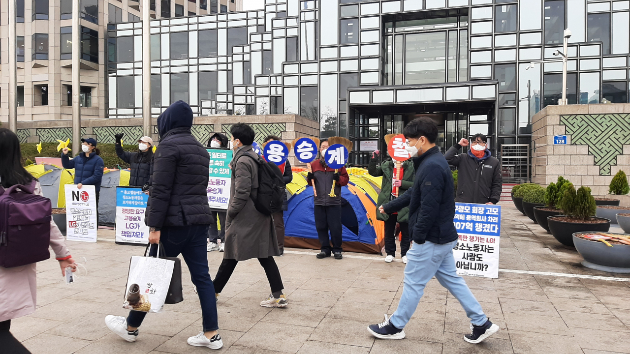 25일 서울 영등포구에 위치한 LG트윈타워에서 선전전을 벌이고 있는 해고 청소노동자 앞으로 통근 버스에서 내린 직원들이 출근하고 있다.주소현 기자/addressh@heraldcorp.com