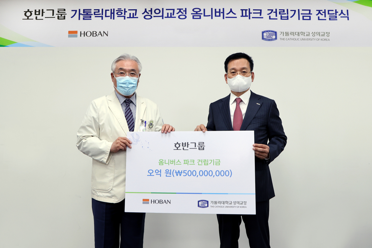 호반그룹은 25일 가톨릭대학교 의료 융복합 공간 ‘옴니버스 파크’ 건립을 위해 5억원을 전달했다. 김상열 호반장학재단 이사장(오른쪽)과 문정일 가톨릭대 의무부총장 겸 의료원장이 이날 서울 서초구 반포동 가톨릭대 성의교정에서 열린 전달식에서 기념촬영을 하고 있다. [호반건설 제공]