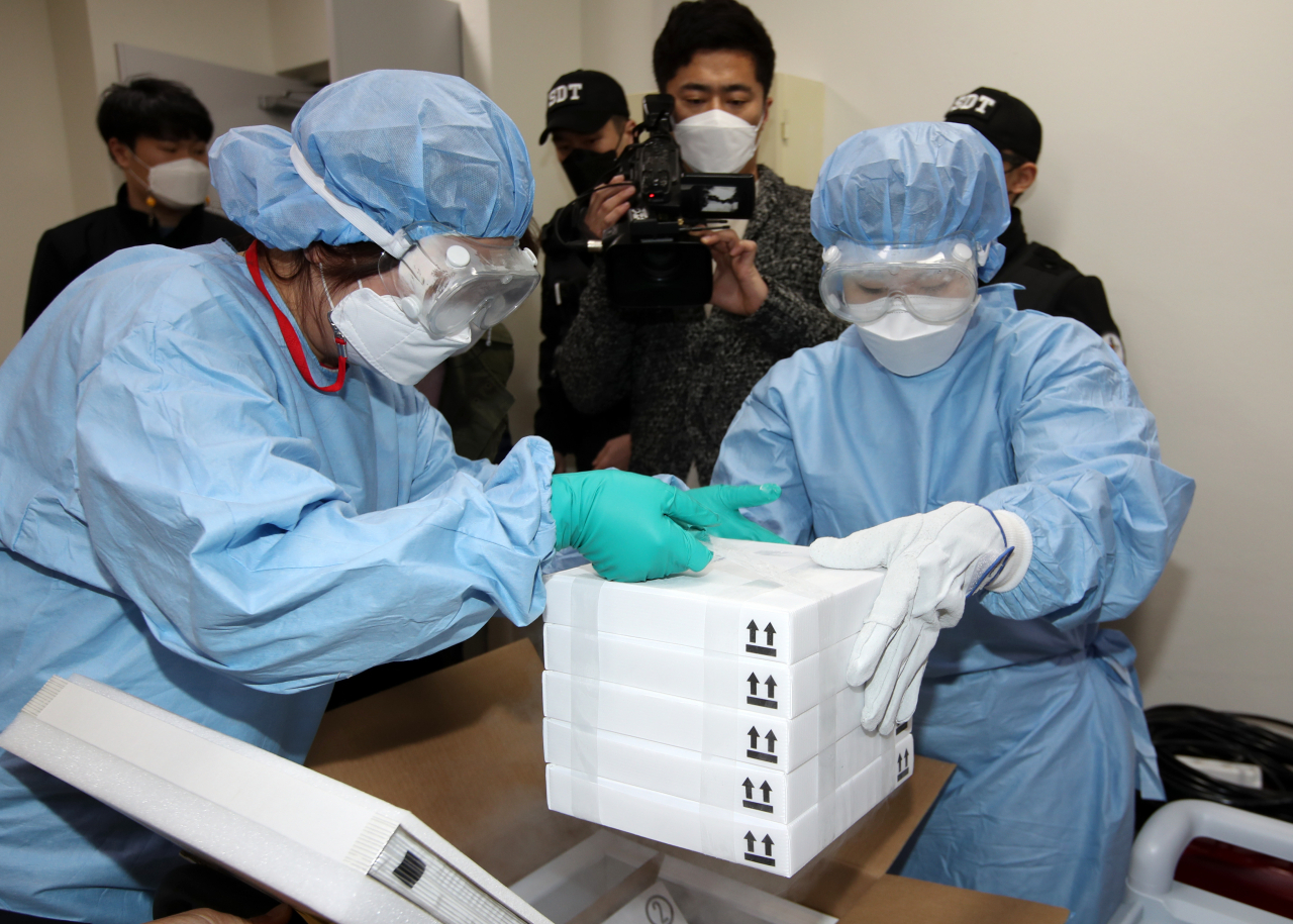 지난 24일 광주 서구 염주체육관에 마련된 예방접종센터에서 방역 관계자들이 다음달 1일부터 만 75세 이상 고령층을 대상으로 접종할 미국 화이자사(社)의 신종 코로나바이러스 감염증(코로나19) 백신을 저장고에 넣기 위해 상자에서 꺼내고 있다. [연합]
