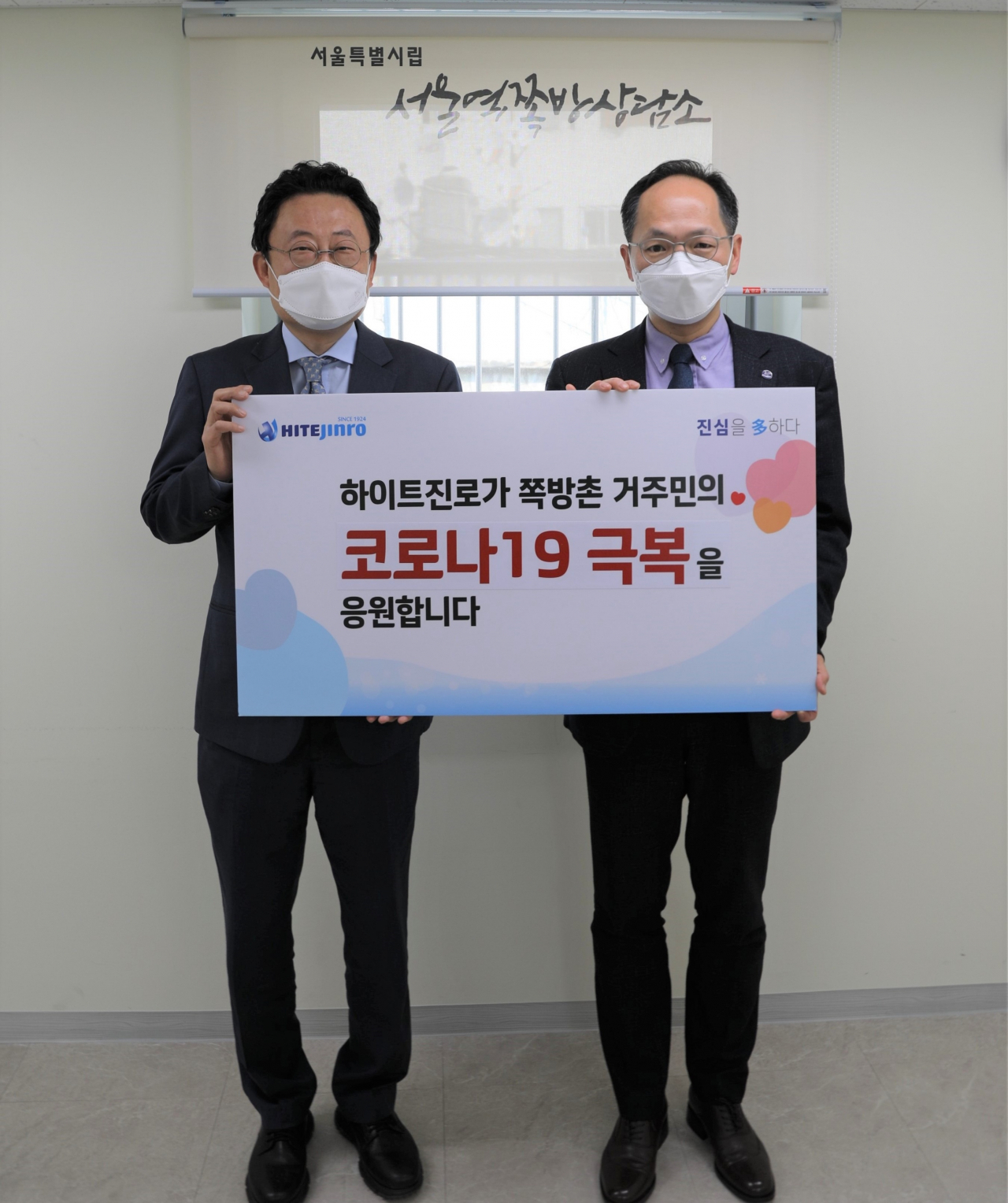 하이트진로 류준형 상무(왼쪽)가 서울역 쪽방상담소에서 김갑록 소장을 만나 쪽방촌 거주민을 위한 마스크(KF-94)를 전달하고 있다. [하이트진로 제공]