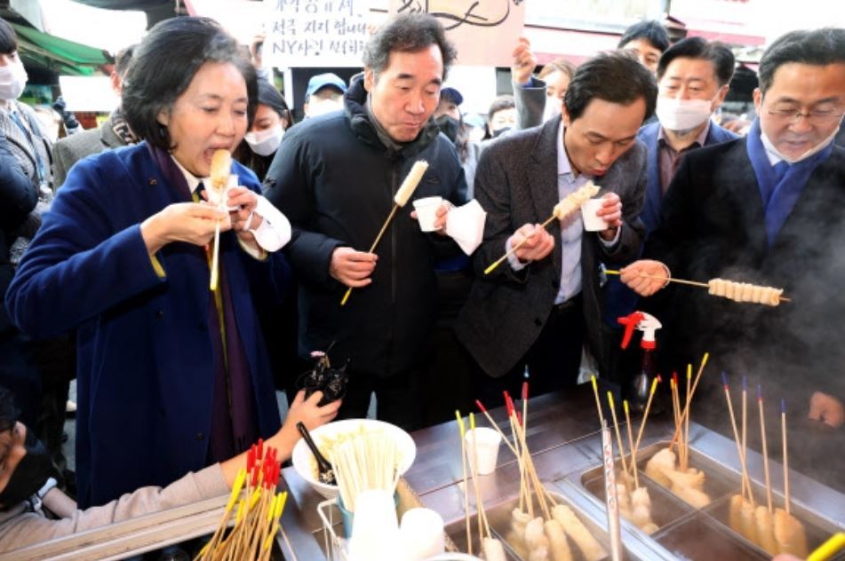 Politicians photographed eating street foods at a traditional market in Seoul on Jan. 23. From left, the Democratic Party's Seoul mayoral candidate Park Young-sun, former chairperson Rep. Lee Nak-yon and Rep. Woo Sang-ho. (Yonhap)