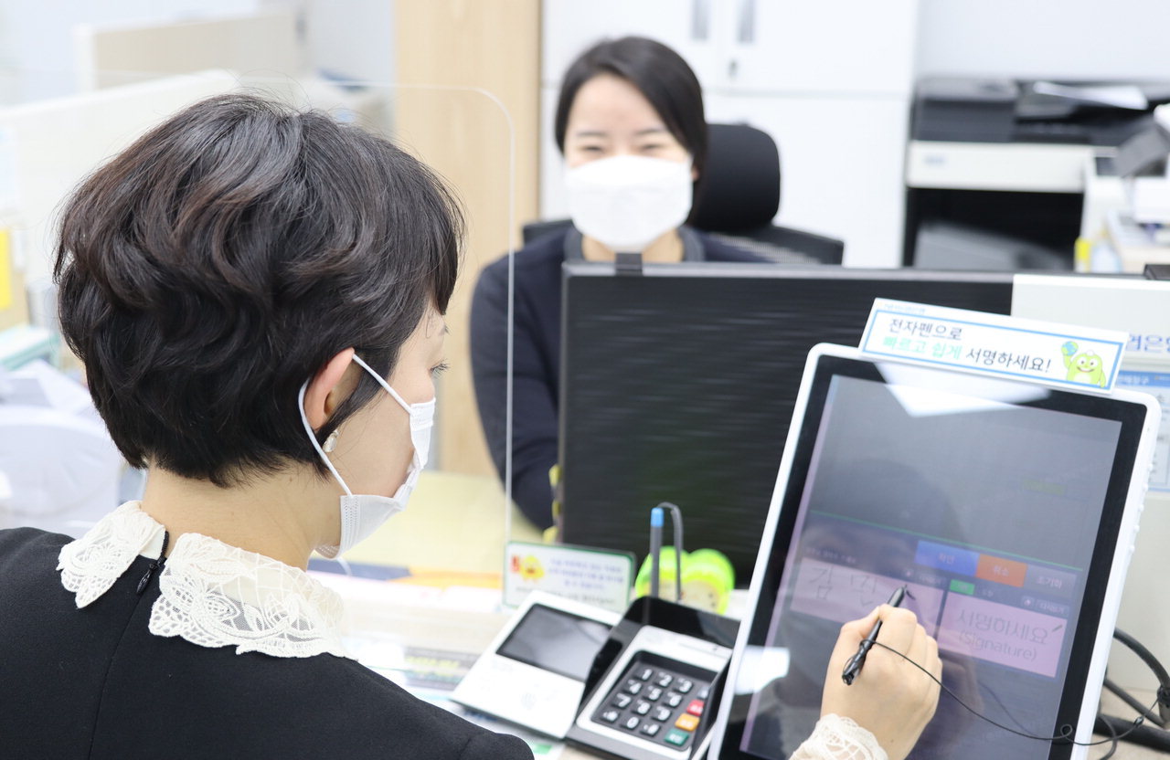 A customer signs documents displayed on a tablet PC installed in a booth at a NH NongHyup Bank branch in Seoul. (NH NongHyup Bank)