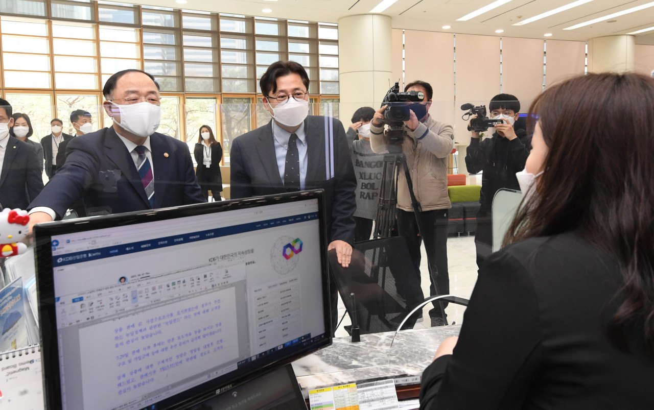 Finance Minister Hong Nam-ki, left, speaks with an employee about the New Deal policy fund at a Korea Development Bank branch in Yeouido, western Seoul on Thursday. (Yonhap)