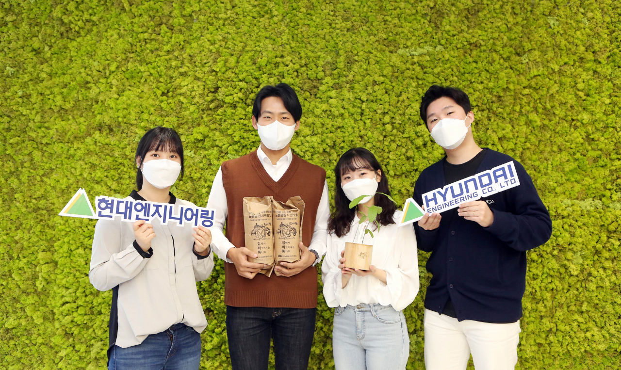 ‘집에서 씨앗 키우는 통나무(이하 집씨통)’에 참여하는 현대엔지니어링 직원들이 도토리 씨앗이 들어있는 나무화분을 들고 사진을 촬영하고 있다. [현대엔지니어링 제공]