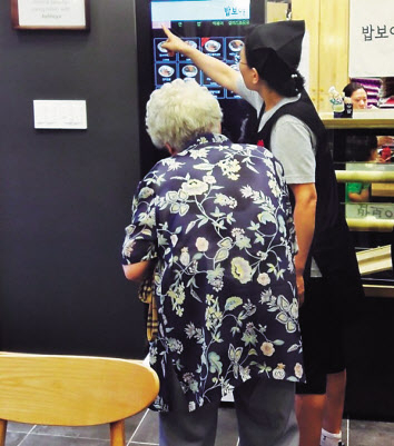 한 노인이 무인단말기 사용법 설명을 듣는 모습. [헤럴드DB]