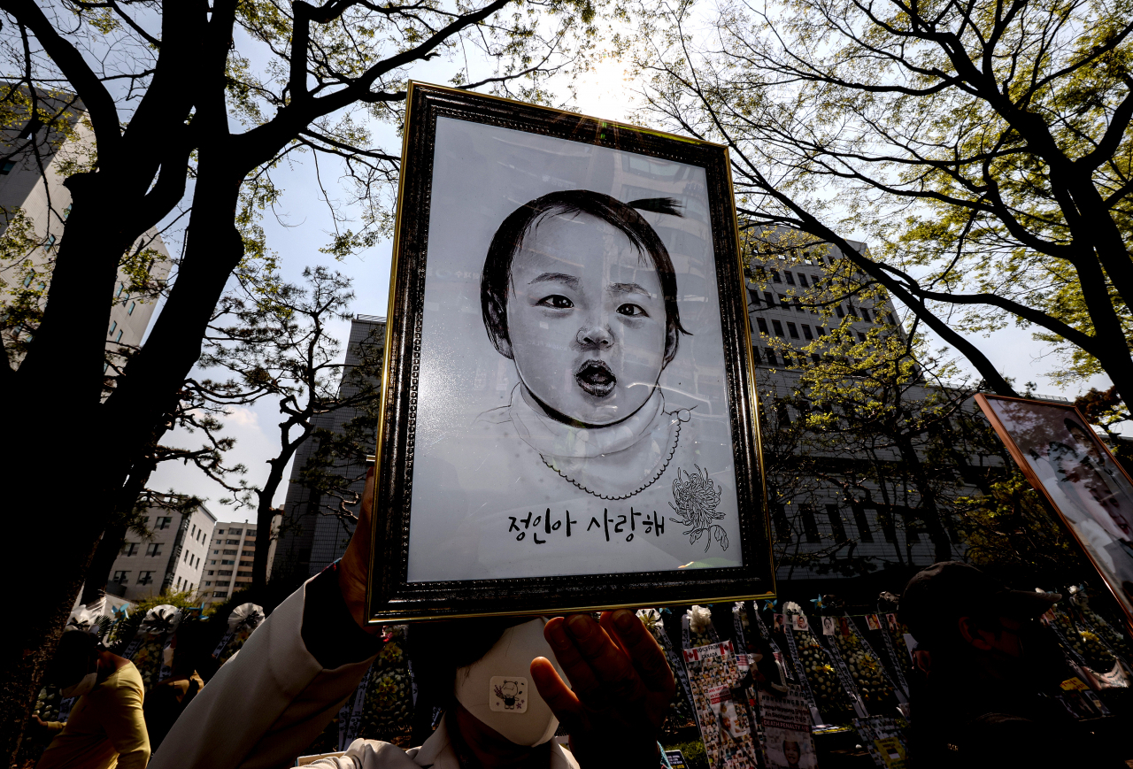 16개월 된 입양 딸 정인이를 학대해 숨지게 한 혐의를 받는 양부모의 5차 공판이 열린 7일 오후 서울 양천구 서울남부지법 입구에서 한 시민이 정인 양의 초상화를 들고 양부모의 엄벌을 촉구하고 있다. [연합]