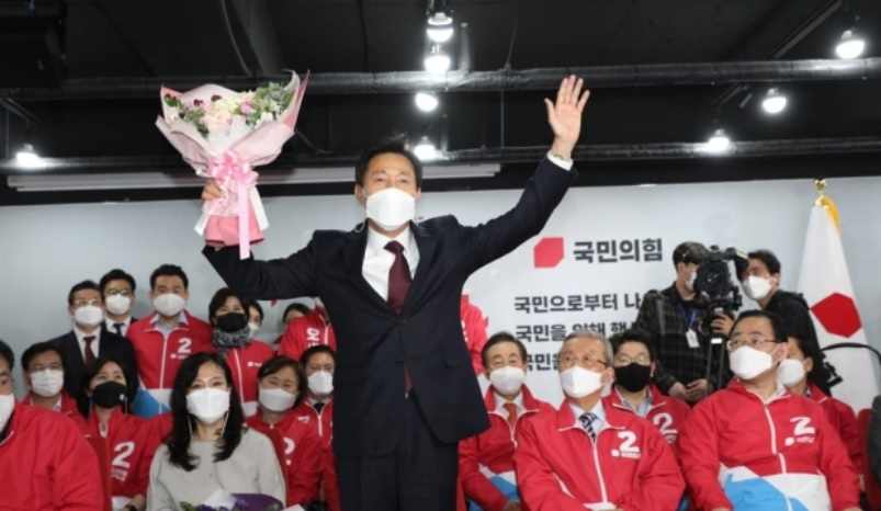 오세훈 서울시장이 8일 자정께 서울 여의도 당사 개표상황실에서 꽃다발을 받고 기뻐하고 있다.[연합]