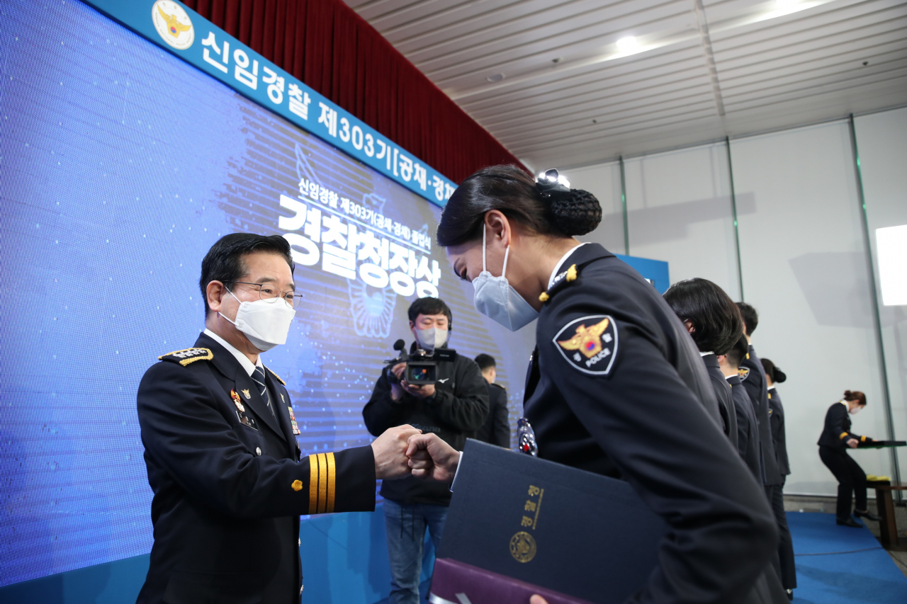 김창룡(왼쪽) 경찰청장이 9일 서울 서대문구 경찰청사에서 중앙경찰학교 신임 경찰 제303기 졸업식에 참석, 한 졸업생에게 졸업장을 주며 주먹 악수를 나누고 있다. 이번 행사는 신종 코로나바이러스 감염증(코로나19) 방역 지침을 고려해 김 청장, 박지영 중앙경찰학교장, 졸업생 대표 17명 등이 참석한 가운데 소규모로 열렸다. 행사는 유튜브를 통해 생중계됐다. [경찰청 제공]
