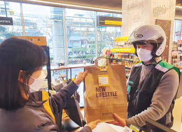 편의점이 올해 본격적인 배달 서비스 강화에 나섰다. 편의점에서 배달원이 배달주문 상품을 건네받고 있는 모습. [이마트24 제공]