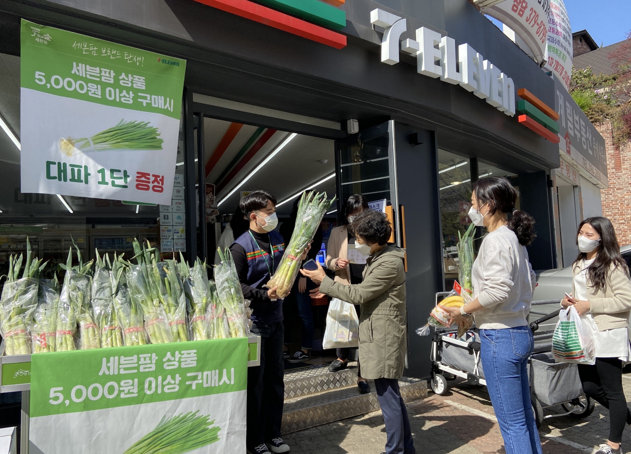 편의점 세븐일레븐이 신선식품 통합 브랜드 ‘세븐팜(Seven Farm)’을 론칭했다. 세븐팜 특화점포인 세븐일레븐 평창점에서 점포 직원이 세븐팜 구매 고객들에게 대파 한 단을 무료로 나눠주고 있다.[세븐일레븐 제공]