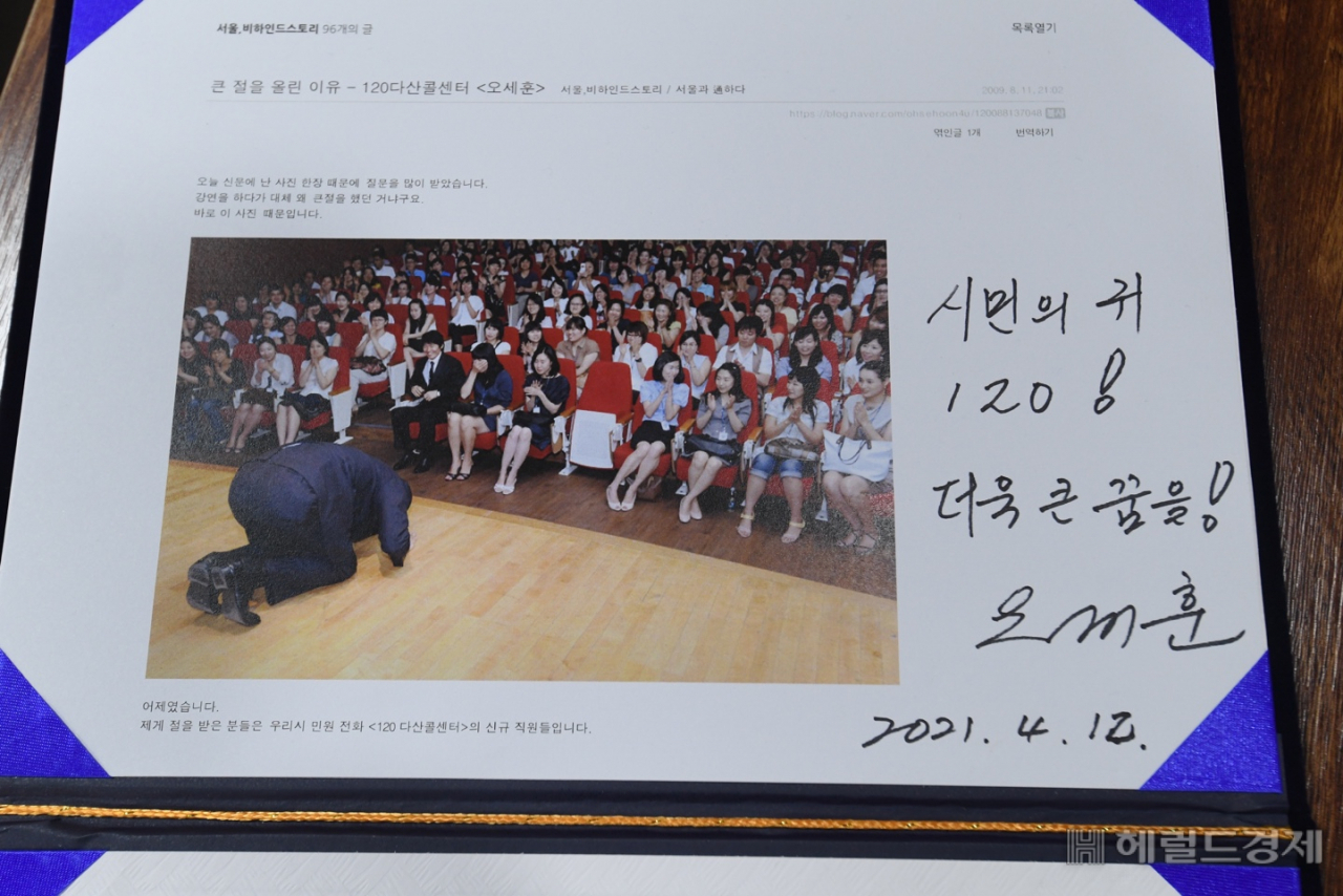 12일 ‘120다산콜재단’을 방문한 오세훈 서울시장이 11년 전 120다산콜센터 출범 당시 찍은 사진첩 등 옛 기록들을 받고 사인했다. [서울시 제공]