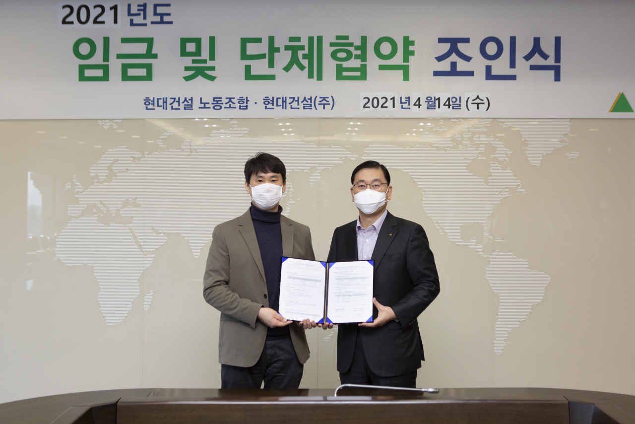 지난 14일 서울 종로구 현대건설 계동사옥에서 열린 ‘2021년도 임금 및 단체협약 체결식’에서 윤영준 현대건설 대표이사(오른쪽)와 김준호 노조위원장이 협약서에 서명한 뒤 기념사진을 찍는 모습. [현대건설 제공]