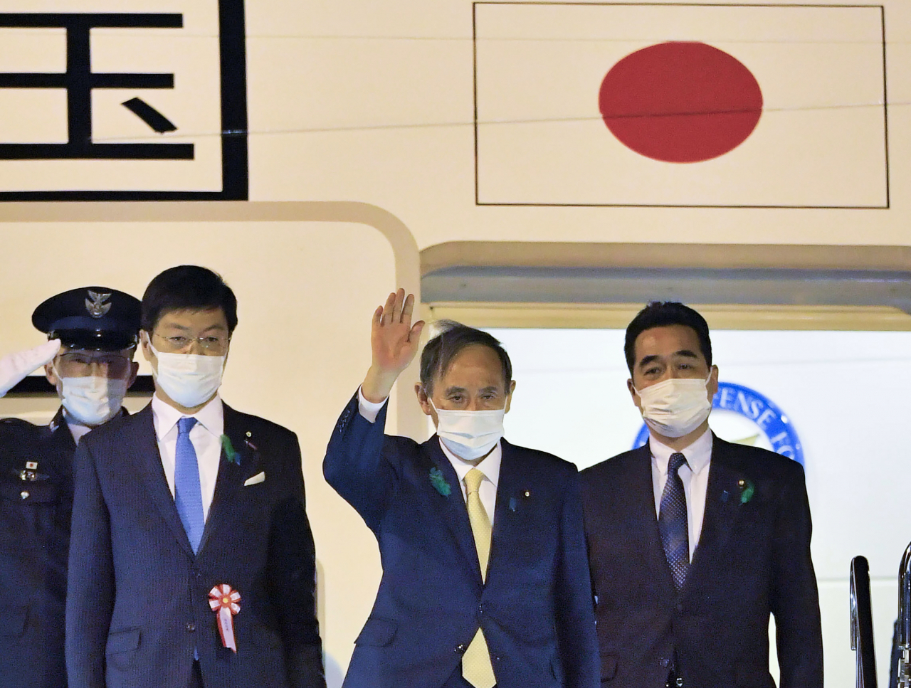 스가 요시히데(菅義偉) 일본 총리가 15일(현지시간) 도쿄 하네다 공항에서 다음날 열리는 미일정상회담 참석하기 위해 전용기에 오르며 손을 흔들고 있다. [AP]
