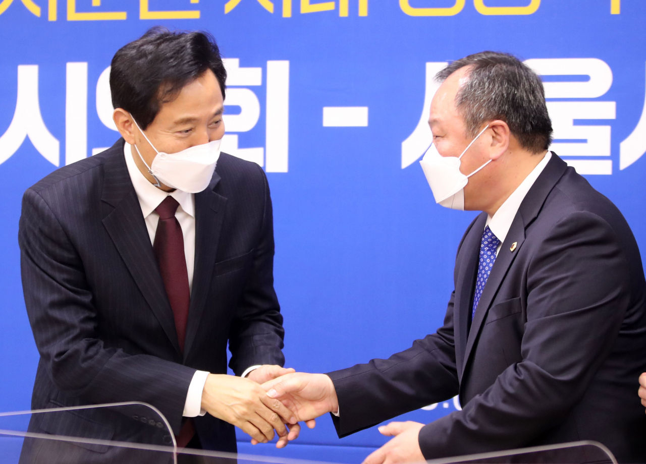 오세훈 서울시장과 김인호 서울시의회 의장이 지난달 19일 오후 서울 중구 서울시의회에서 열린 '서울시의회-서울시 업무협약식을 마친 뒤 악수하고 있다. 연합뉴스