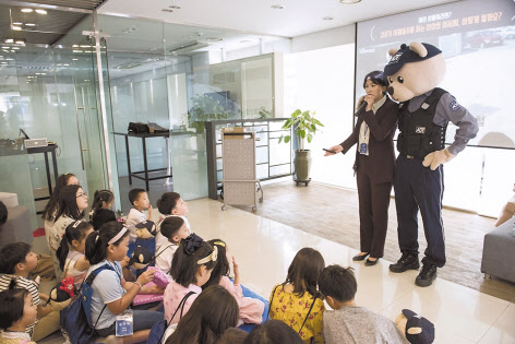 ADT캡스 직원이 친근감을 주는 모습으로 어린이들에게 교통안전에 대한 교육을 하고 있다(왼쪽 사진). 스마트폰으로 어린이 통학차량의 운행 정보를 확인하는 모습. [ADT캡스·에스원 제공]