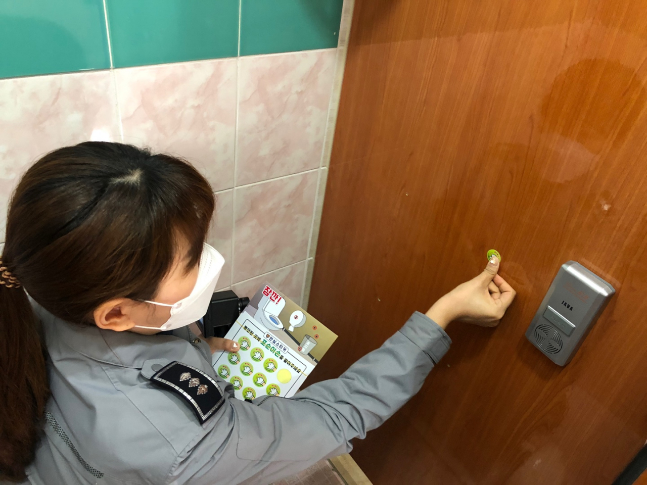 서울 송파경찰서 경찰관이 관내 한 학교에서 불법 촬영이 의심되는 곳에 ‘포순이 손’ 스티커를 붙이고 있다. [송파경찰서 제공]