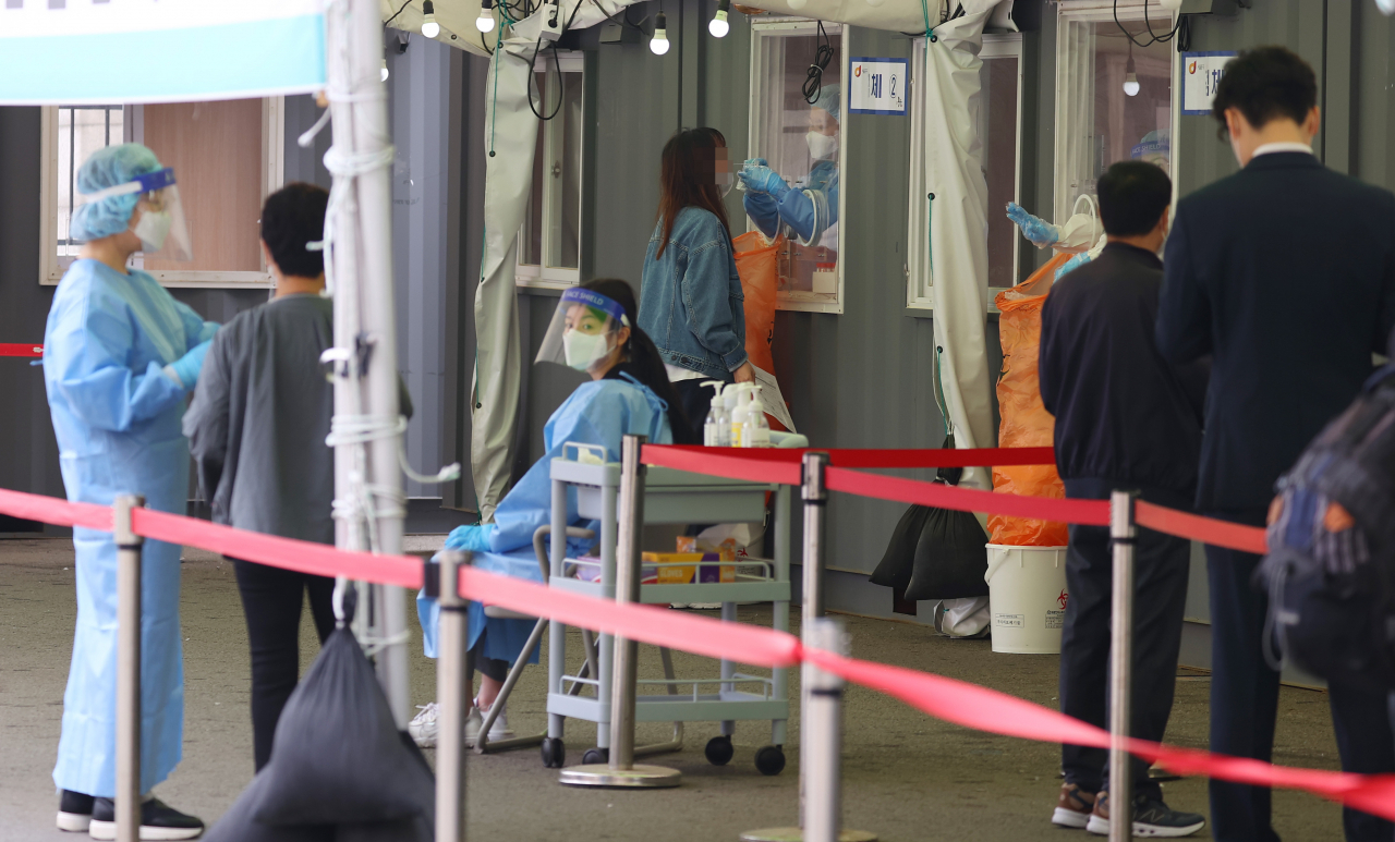 지난 22일 오전 서울역 앞에 마련된 임시선별검사소를 찾은 시민들이 검체 검사를 기다리고 있다. [연합]