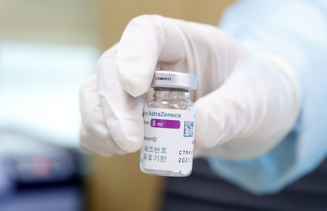 Health care worker at a Seoul inoculation center holds  out a vial of AstraZeneca vaccine. (Yonhap)
