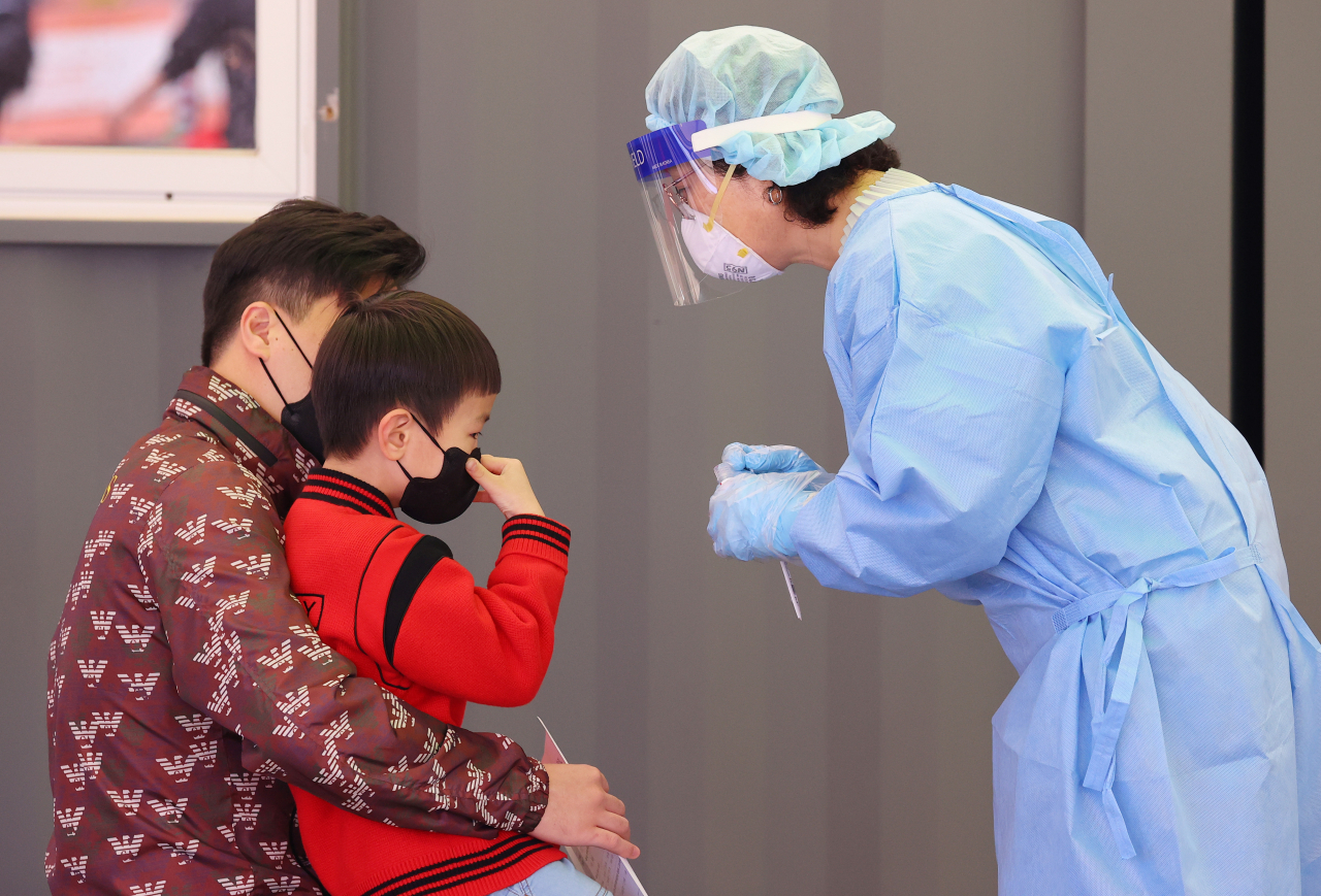 25일 오전 서울역광장에 마련된 코로나19 임시선별검사소에서 한 어린이가 아빠 무릎에 앉아 검체 검사를 받고 있다. 중앙방역대책본부에 따르면 이날 0시 기준 코로나19 신규 확진자 수는 644명을 기록했다. 지날 20일 이후 닷새 만에 700명 아래로 신규 확진자 수가 줄었지만, 이는 평일 대비 주말 검사 건수가 대폭 줄어든 영향에 따른 것으로 추정돼 확산세가 꺾인 것으로 보기는 어려운 상황이다. 연합뉴스