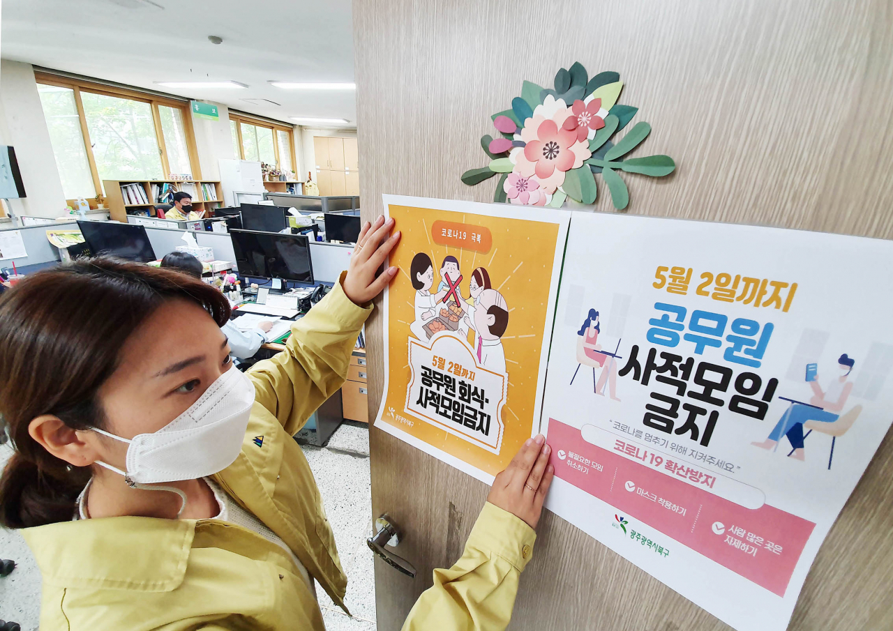 지난 26일 오호 광주 북구청에서 직원들이 코로나19 공무원 회식·모임 전면 금지 시행 안내문을 부착하고 있다. [연합]