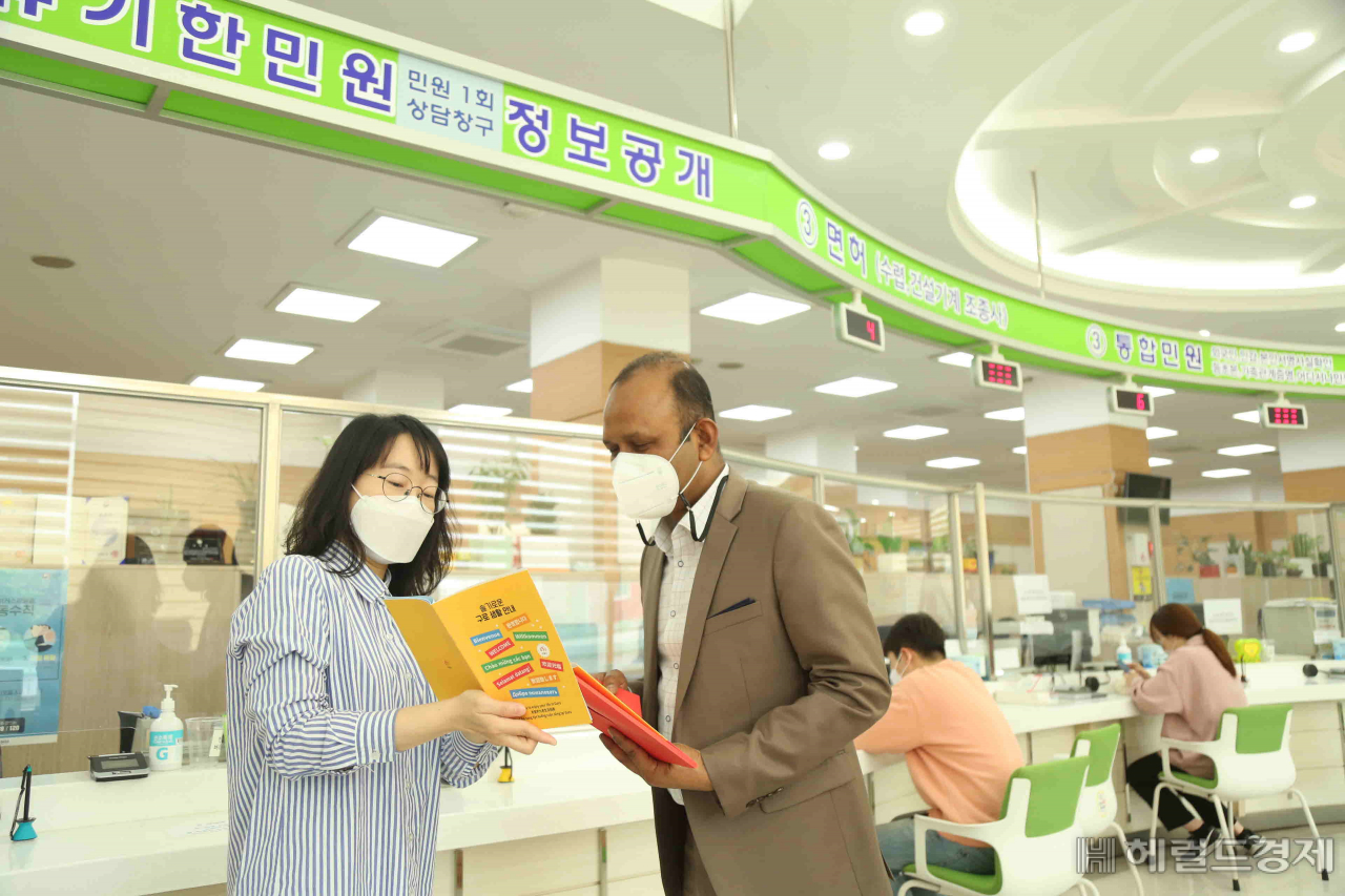 구로구 관계자가 전입하는 외국인 주민에게 슬기로운 구로생활 팸플릿을 보여 주며 설명하고 있다. [구로구 제공]