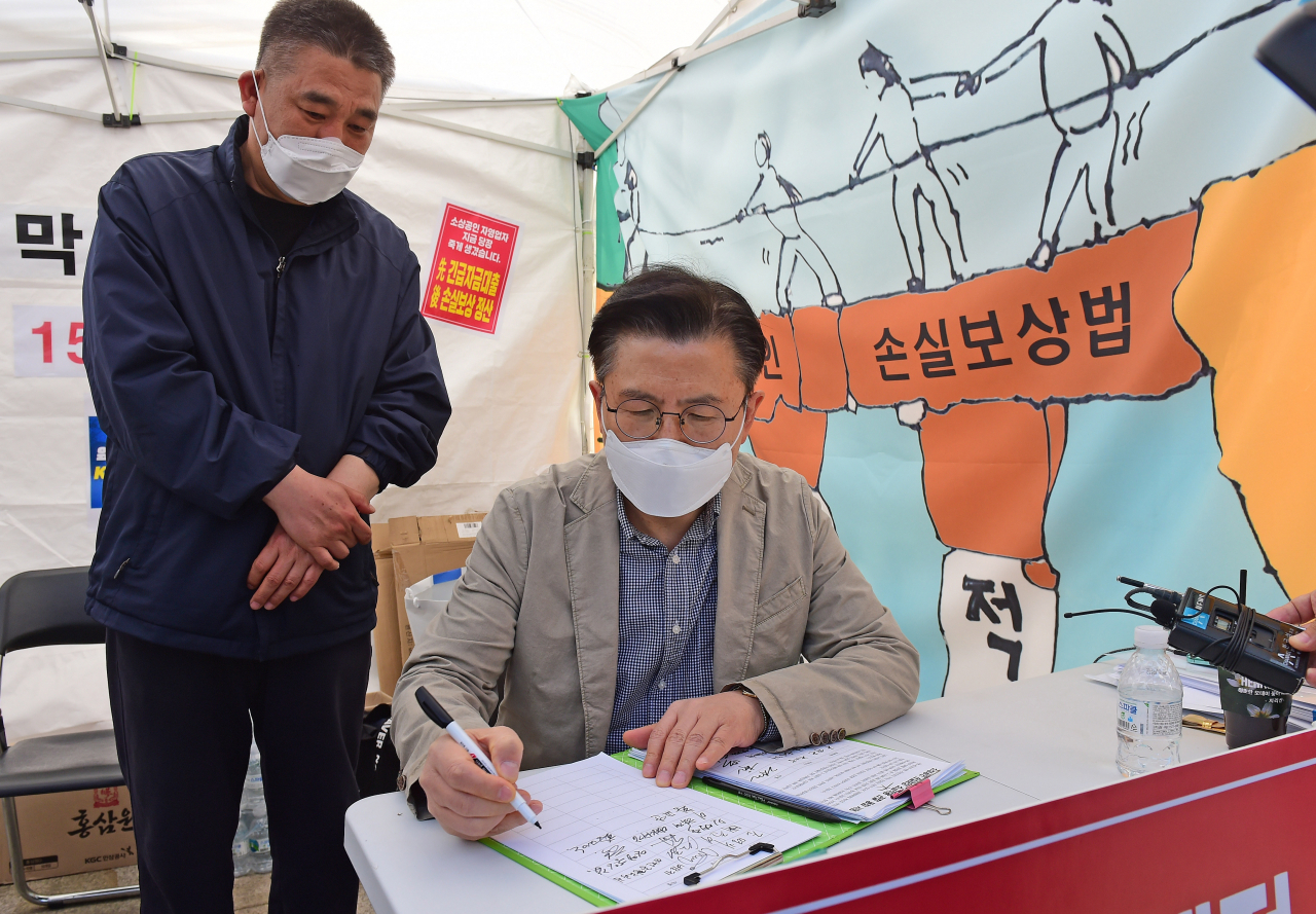 황교안 전 미래통합당 대표(오른쪽)가 26일 서울 여의도 국회 본청 앞 국민의힘 최승재 의원과 소상공인들의 코로나19에 따른 손실보상 소급적용 입법 요구 천막농성장을 찾아 서명하고 있다. [연합]