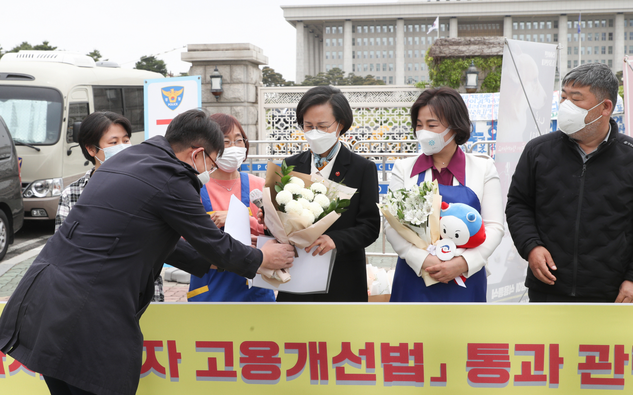 29일 국회 앞에서 열린 가사노동자 고용개선법 통과 관련 기자회견에서 노동단체 관계자가 법안을 발의한 강은미 정의당 의원에게 꽃다발을 전하고 있다.[연합]