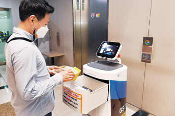 ‘LG 클로이 서브봇 ’이 고객에게 편의점 주문 물건을 전달하고 있는 모습. [LG전자 제공]