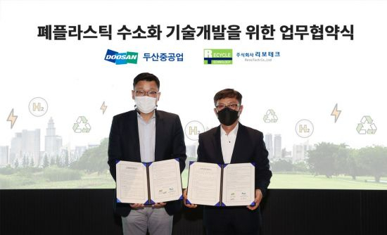 분당두산타워에서 열린 '폐플라스틱 수소화 기술 개발을 위한 업무 협약식'에서 두산중공업 송용진 부사장(왼쪽)과 리보테크 황병직 대표이사가 서명을 마친 후 기념촬영을 하고 있다. [두산중공업 제공]