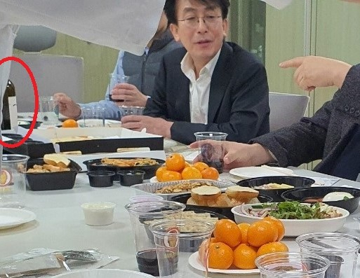 지난해 12월 8일 정기현 국립중앙의료원장이 중증 신종 코로나바이러스 감염증(코로나19) 환자 치료를 위한 모듈병원 3층에서 식사자리를 갖고 있다. 와인 한 병이 테이블 위에 올려져 있고, 와인으로 추정되는 음료가 플라스틱 잔에 담겨 있다.