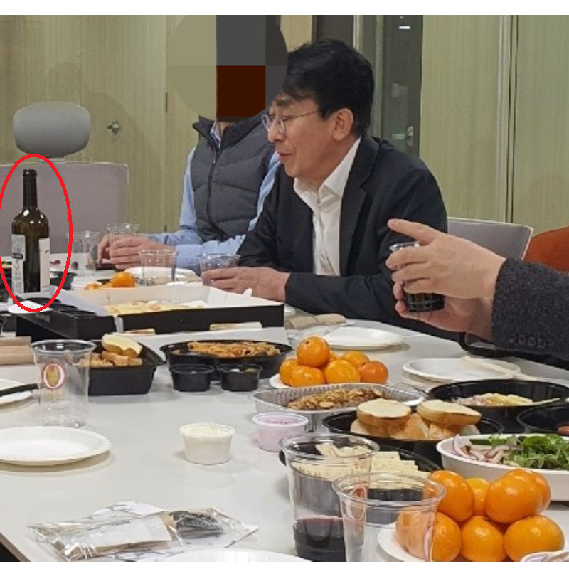 지난해 12월 8일 정기현 국립중앙의료원장이 중증 신종 코로나바이러스 감염증(코로나19) 환자 치료를 위한 모듈병원 3층에서 식사 자리를 갖고 있다. 와인 한 병이 테이블 위에 올려져 있고, 와인으로 추정되는 음료가 플라스틱 잔에 담겨 있다.