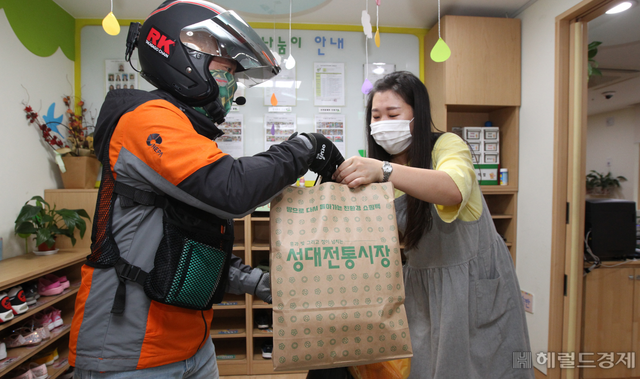 한 구민이 성대전통시장에서 배달된 구매 물품을 전달 받고 있다. [동작구 제공]