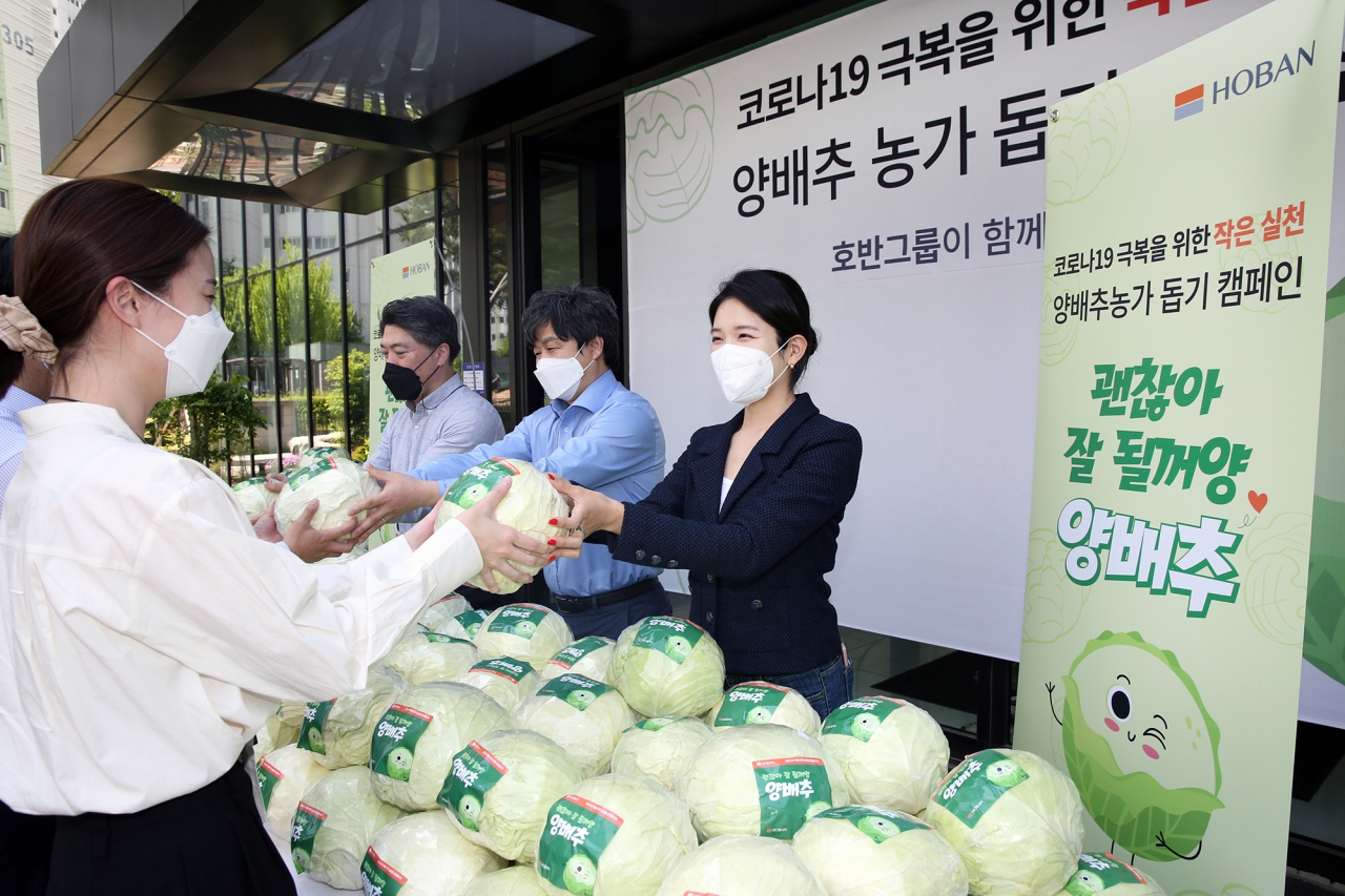 호반그룹은 13일 양배추 농가 돕기 캠페인을 진행했다. 김윤혜 호반프라퍼티 부사장(가운데)이 임직원에게 양배추를 나누고 있다.
