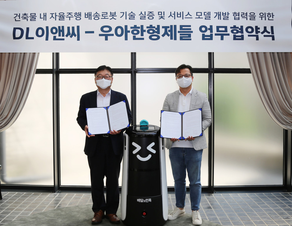 김요섭 우아한형제들 로봇사업실장(오른쪽)과 나재현 DL이앤씨 주택사업본부 엔지니어링실장 (왼쪽)이 지난 13일 서울 용산구 드림하우스 갤러리에서 ‘건물 내 배송로봇 기술 실증 및 서비스 모델 개발 협력을 위한 업무협약(MOU)’을 체결하고 기념 촬영을 하고 있다. [배달의민족 제공]