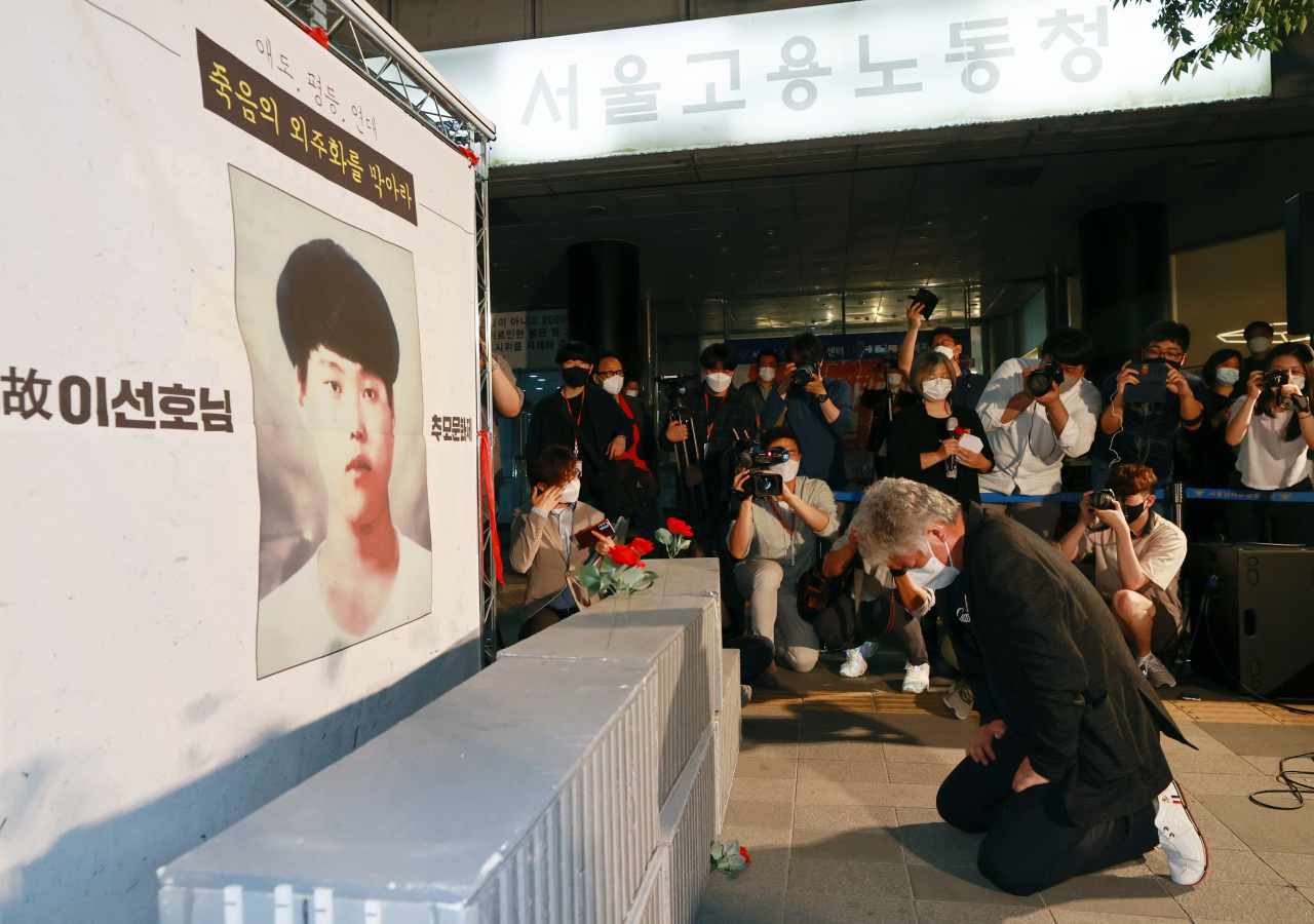 평택항에서 일하다 사고로 숨진 20대 청년 노동자 고 이선호 씨의 부친 이재훈 씨가 지난 13일 오후 서울 중구 서울지방고용청 앞에서 열린 추모문화제에서 아들의 얼굴이 새겨진 현수막 앞에 무릎을 꿇고 오열하고 있다. [연합]
