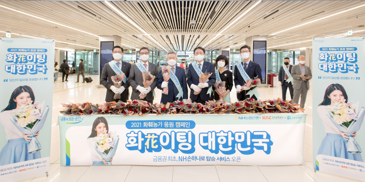 지난 17일 김포공항에서 권준학 농협은행장(왼쪽에서 4번째), 손창완 한국공사공사 사장(왼쪽에서 3번째), 김학수 금융결제원장(왼쪽에서 2번째)이 금융권 최초 농협은행 생체정보 탑승 서비스 개시를 기념하여 승객들에게 화훼농가 돕기 꽃나누기 행사를 하고 있다.