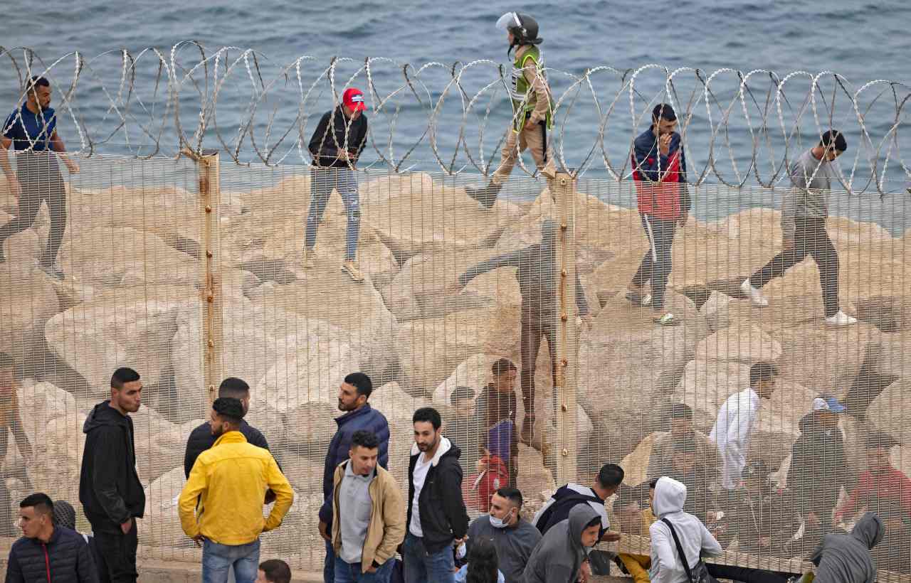 Moroccan migrants slip through a fence in the northern town of Fnideq in an attempt to cross the border from Morocco to Spain's North African enclave of Ceuta on May 18, 2021. (AFP-Yonhap)