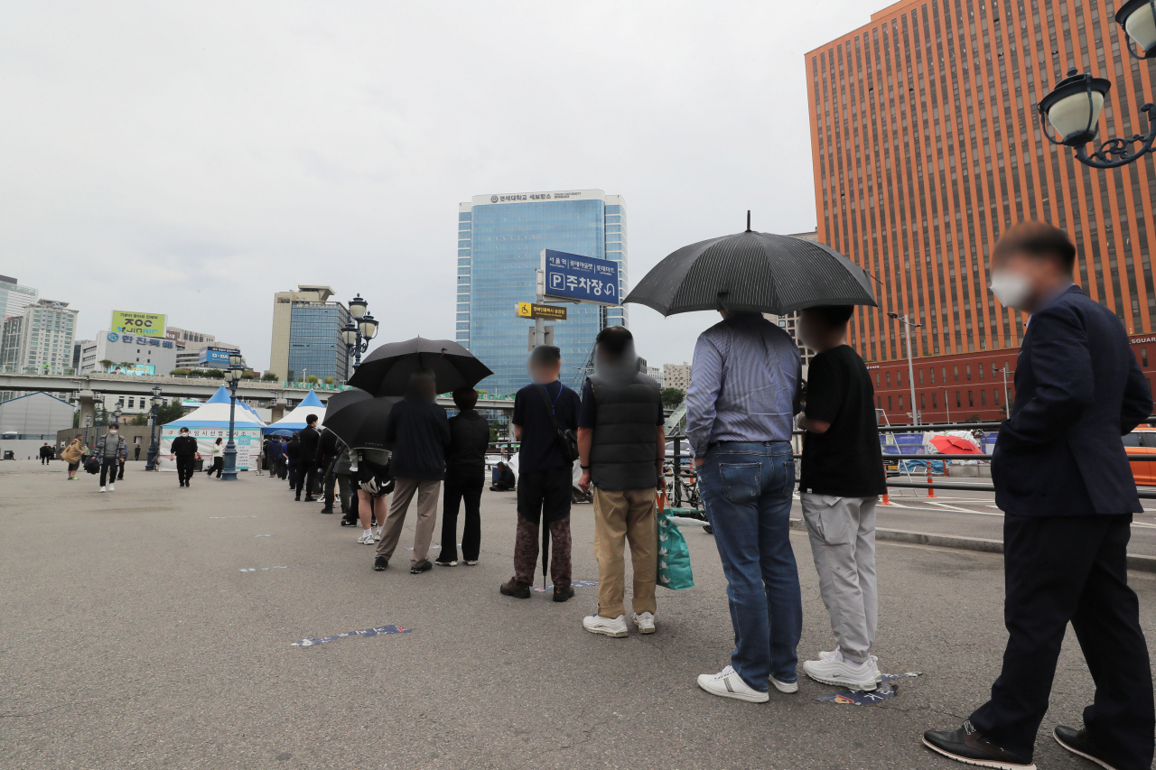 20일 오전 서울역광장에 마련된 임시 선별진료소에 코로나19 검사를 받기 위한 시민들의 줄이 길게 늘어져 있다. [연합]