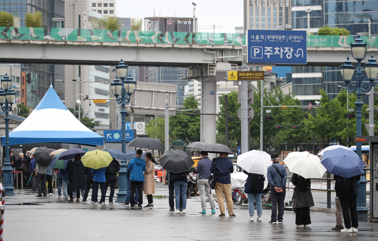 비가 내린 21일 오전 서울 중구 서울역 앞에 마련된 신종 코로나바이러스 감염증(코로나19) 임시 선별검사소에서 우산을 쓴 시민들이 검사를 기다리고 있다. [연합]