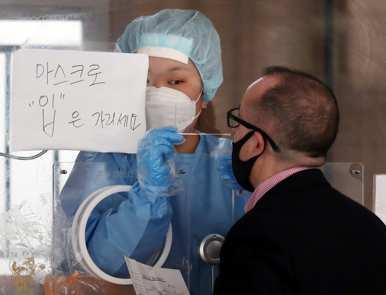 비가 내린 21일 오전 서울 중구 서울역 앞에 마련된 신종 코로나바이러스 감염증(코로나19) 임시 선별검사소에서 외국인이 검체 채취를 받고 있다. 연합뉴스