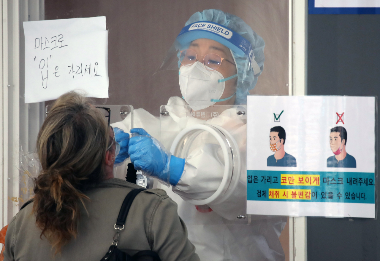 비가 내린 21일 오전 서울 중구 서울역 앞에 마련된 신종 코로나바이러스 감염증(코로나19) 임시 선별검사소에서 외국인이 검체 채취를 받고 있다. 연합]