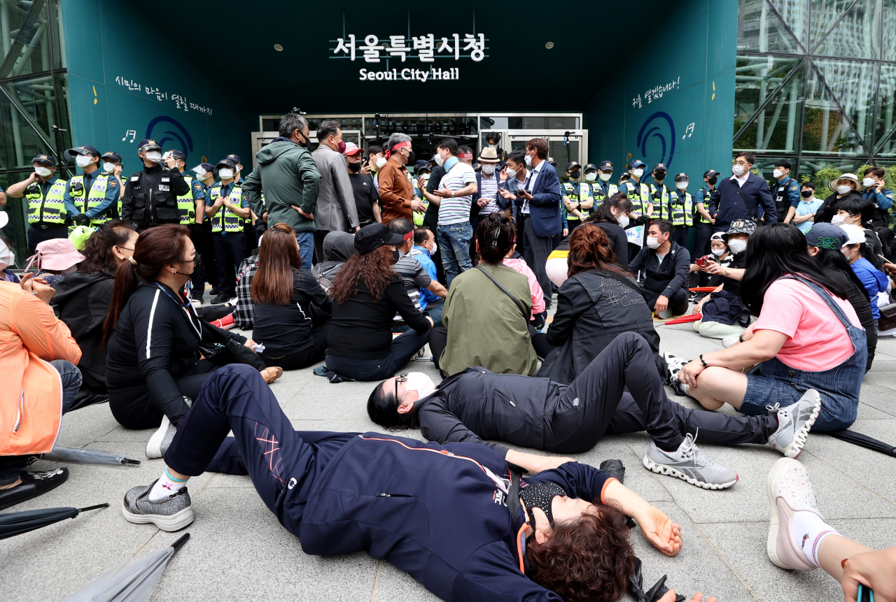 지난 20일 오후 한국유흥음식업중앙회·한국단란주점업중앙회·한국콜라텍협회 관계자들과 업주들이 정부에 집합금지 해제와 손실보상법 통과를 촉구하며 서울 중구 서울시청 내부로 진입하던 중 경찰에 막히자 자리에 누워 농성 하고 있다. [연합]