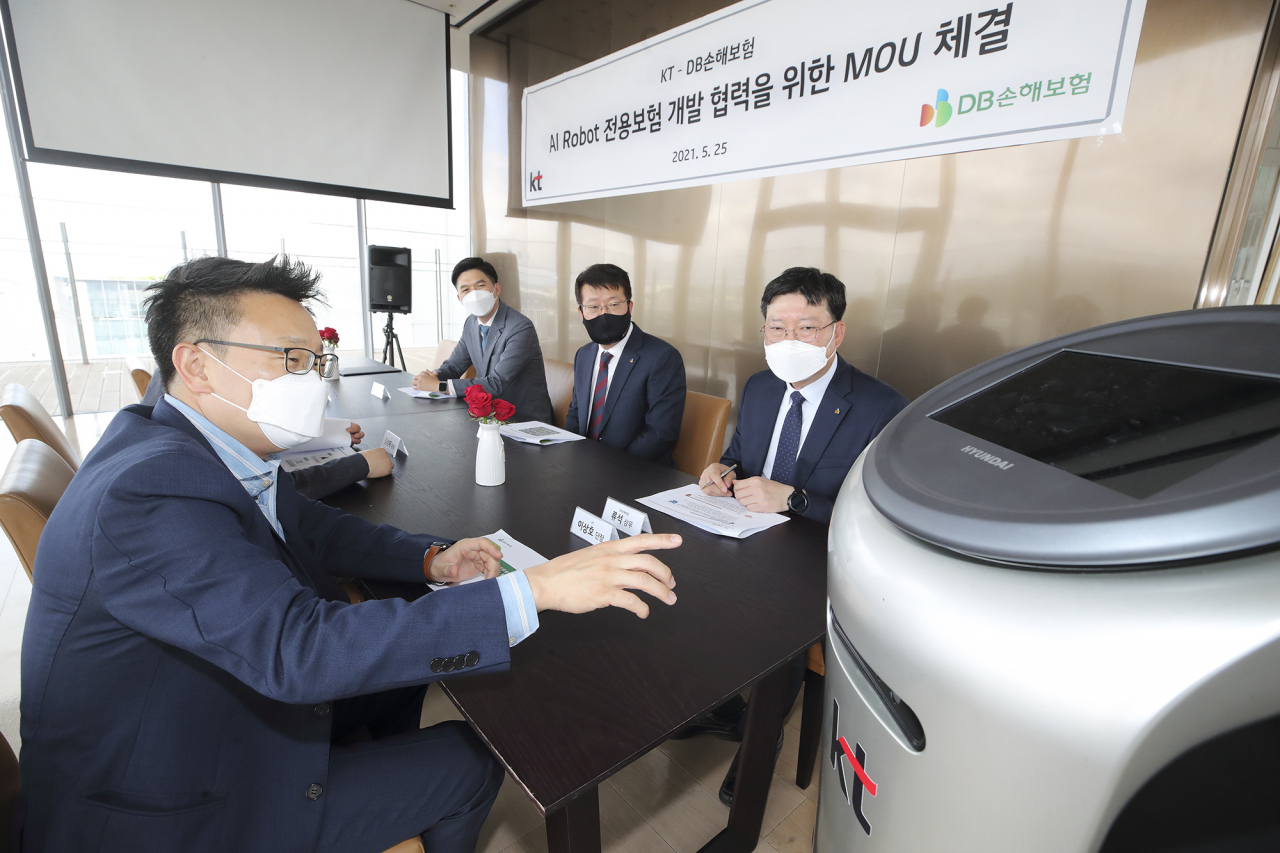 KT AI Robot사업단 이상호 단장(왼쪽)과 DB손해보험 류석 상무(오른쪽)를 비롯한 관계자들이 인공지능(AI) 서비스 로봇 전용 보험에 대해 논의하고 있다. [KT 제공]