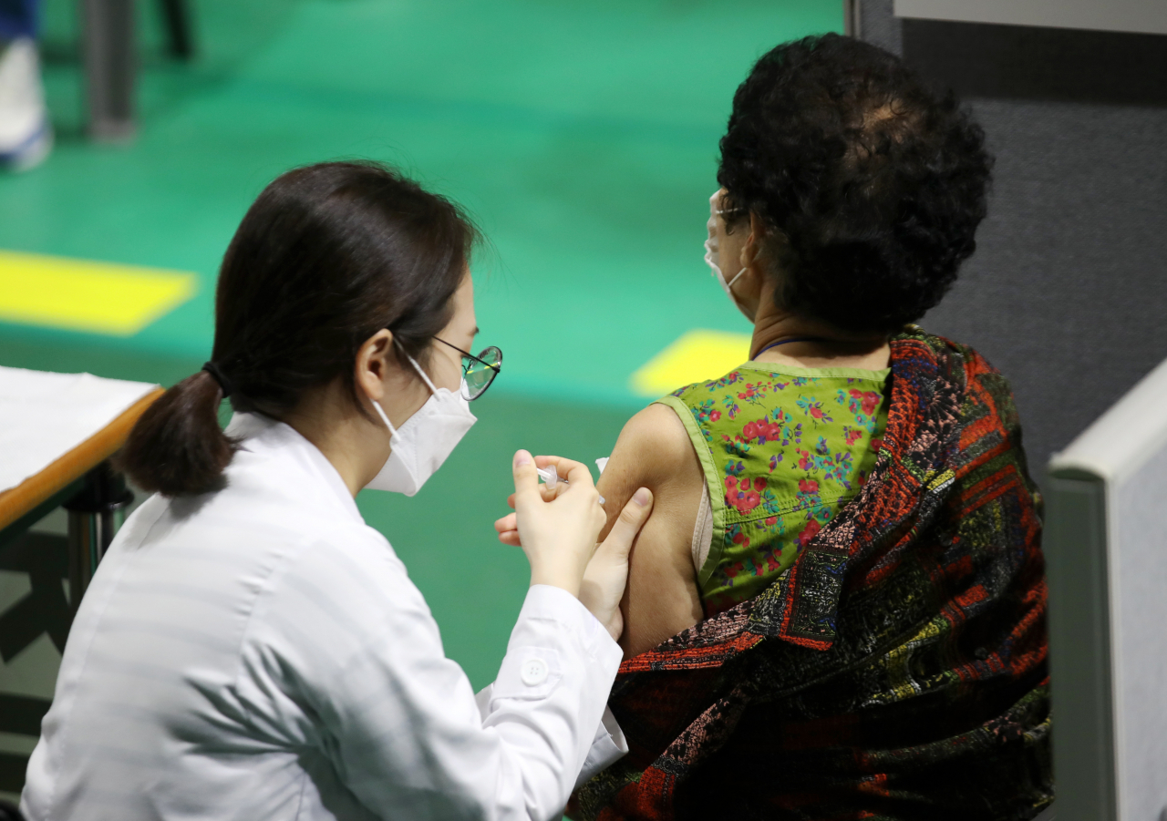 지난 24일 오전 광주 서구 염주체육관에 마련된 코로나19 예방접종센터에서 한 의료진이 시민들에게 백신을 접종하고 있다. [연합]