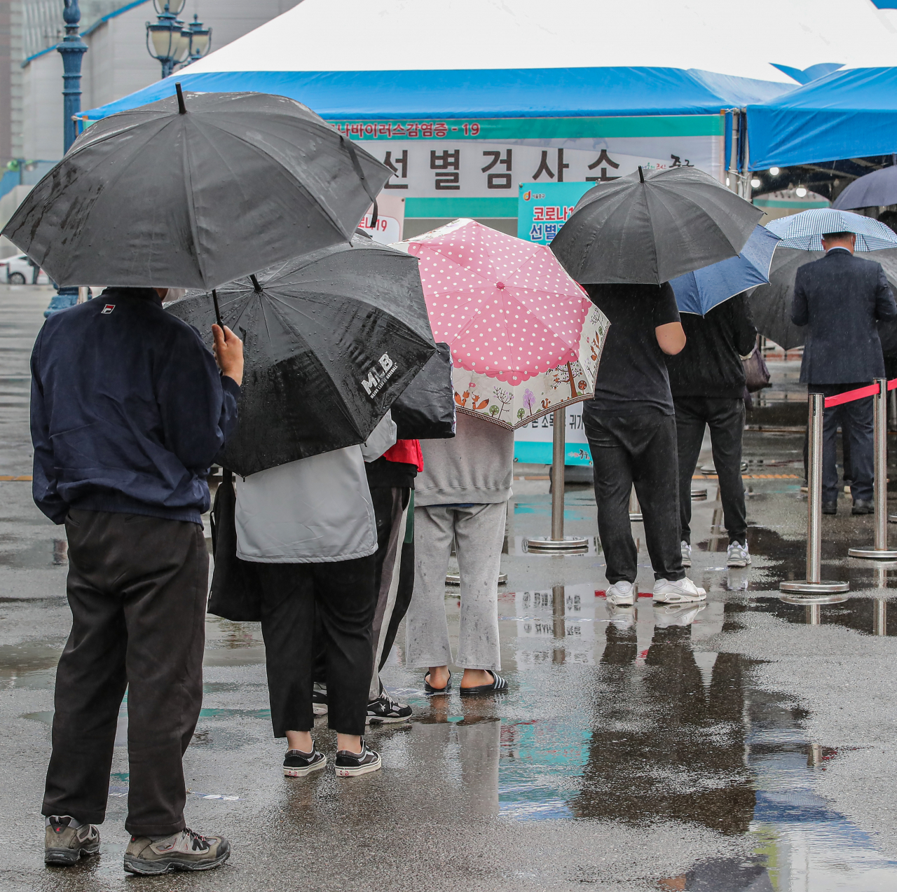 27일 오전 서울 중구 서울역에 설치된 임시 선별검사소에서 시민들이 코로나19 검사를 받기 위해 우산을 쓰고 줄지어 서 있다. 이날 보건 당국은 코로나19 신규확진자가 629명 기록했다고 발표했다. 연합뉴스