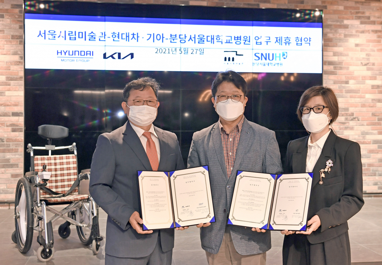 서울 서초구 제로원에서 진행된 업무협약(MOU) 체결식에서 (왼쪽부터) 분당서울대학교병원 김지수 기획조정실장, 기아 신동수 경영전략실장, 서울시립미술관 백지숙 관장이 자율주행 시스템이 탑재될 전동 휠체어 앞에서 기념 사진을 촬영하고 있다. [현대차·기아 제공]
