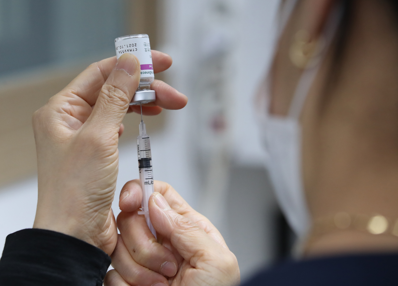 A health care worker at a Seoul clinic fills a syringe with a dose of AstraZeneca COVID-19 vaccine. (Yonhap)