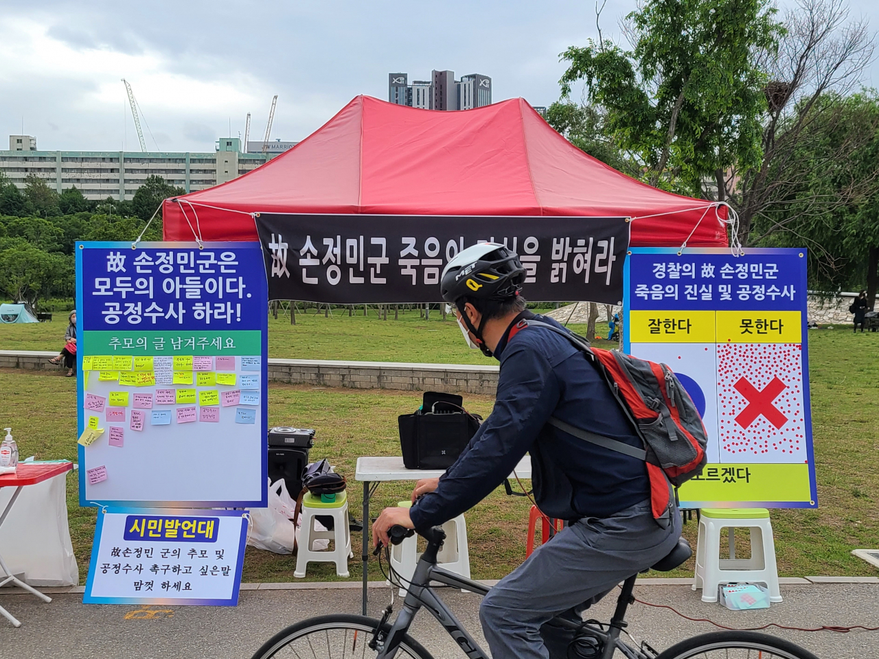 29일 오후 서울 서초구 반포한강공원 수상택시 승강장 인근에 설치된 '고(故) 손정민 씨 추모·공정수사 촉구 시민 발언대'를 지나가던 한 시민이 살펴보고 있다. [연합]